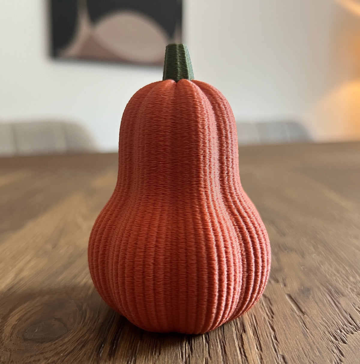 3D geprinte pompoen decoratie in terracotta op houten tafel – najaarsinterieur